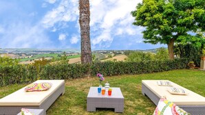 A terrace with two lounge chairs, a small table with drinks, and a view of rolling hills. - 3 bedroom amazing home in Montelabbate (Montelabbate)
