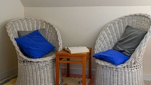 Two wicker chairs with blue and gray cushions, a small wooden table, and a book.