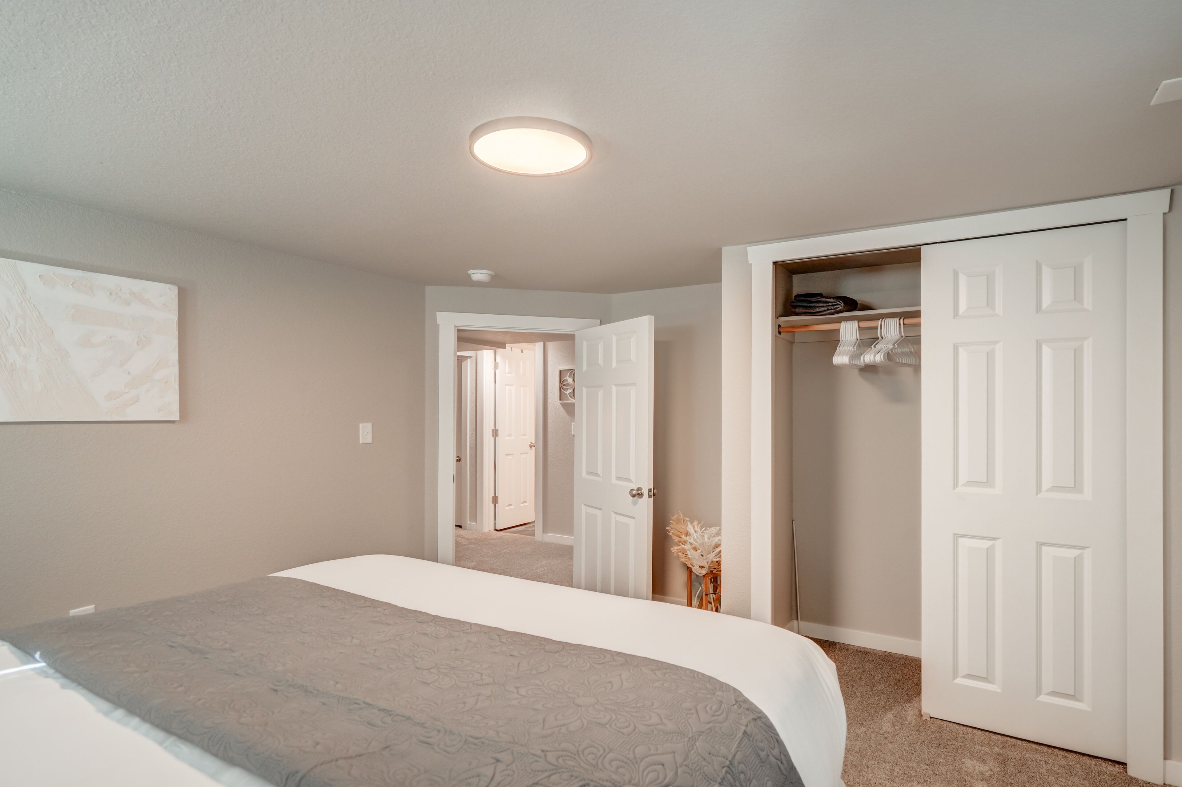 A bedroom with a bed, a closet, and a hallway leading to another room.