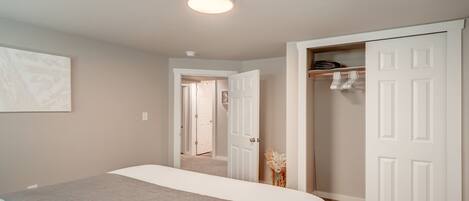 A bedroom with a bed, a closet, and a hallway leading to another room.