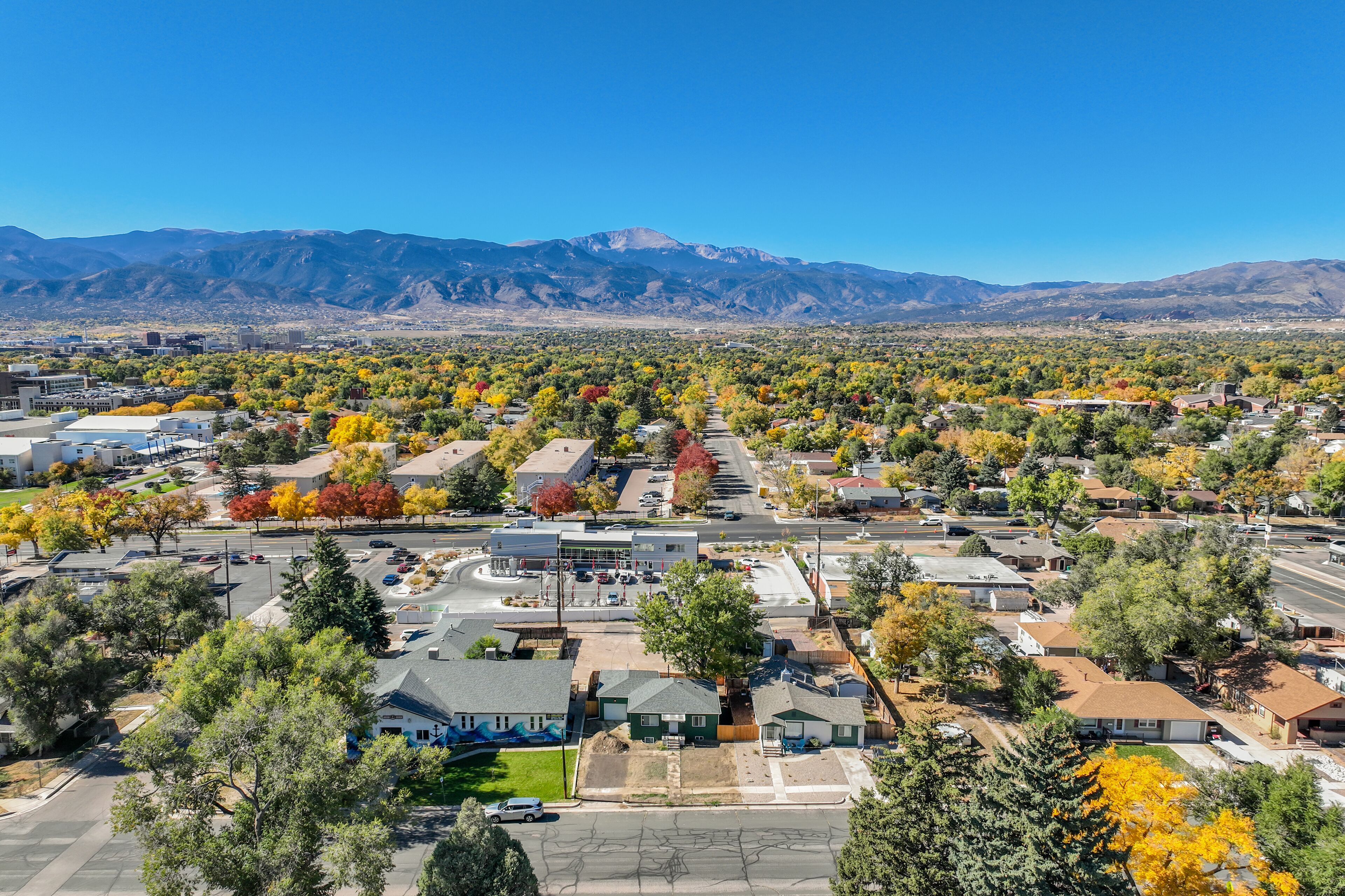 An aerial view of a suburban area with residential houses, streets, and a mountain range in the background.