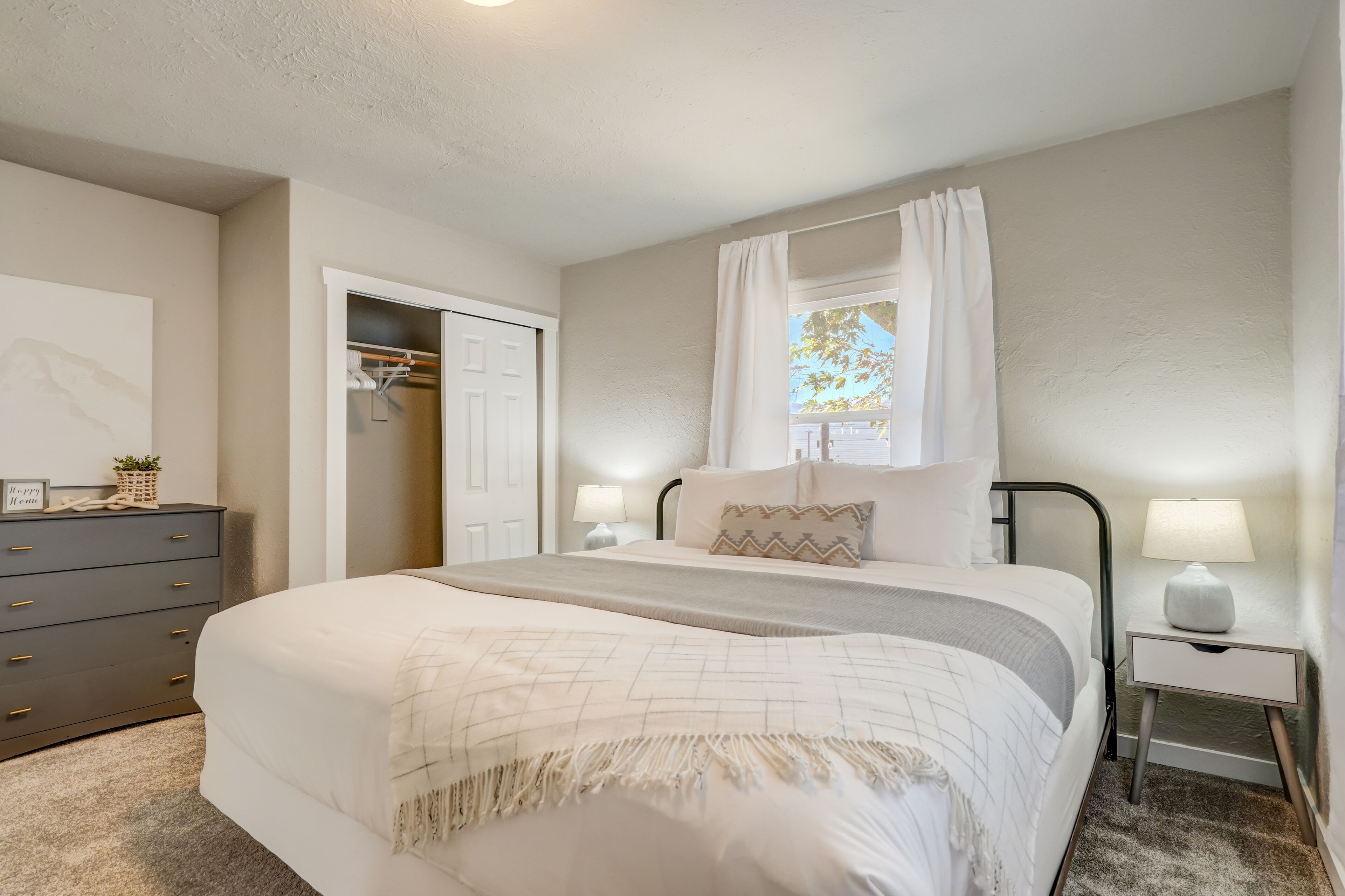 A bedroom with a large bed, bedside tables, a wardrobe, and a window with curtains.