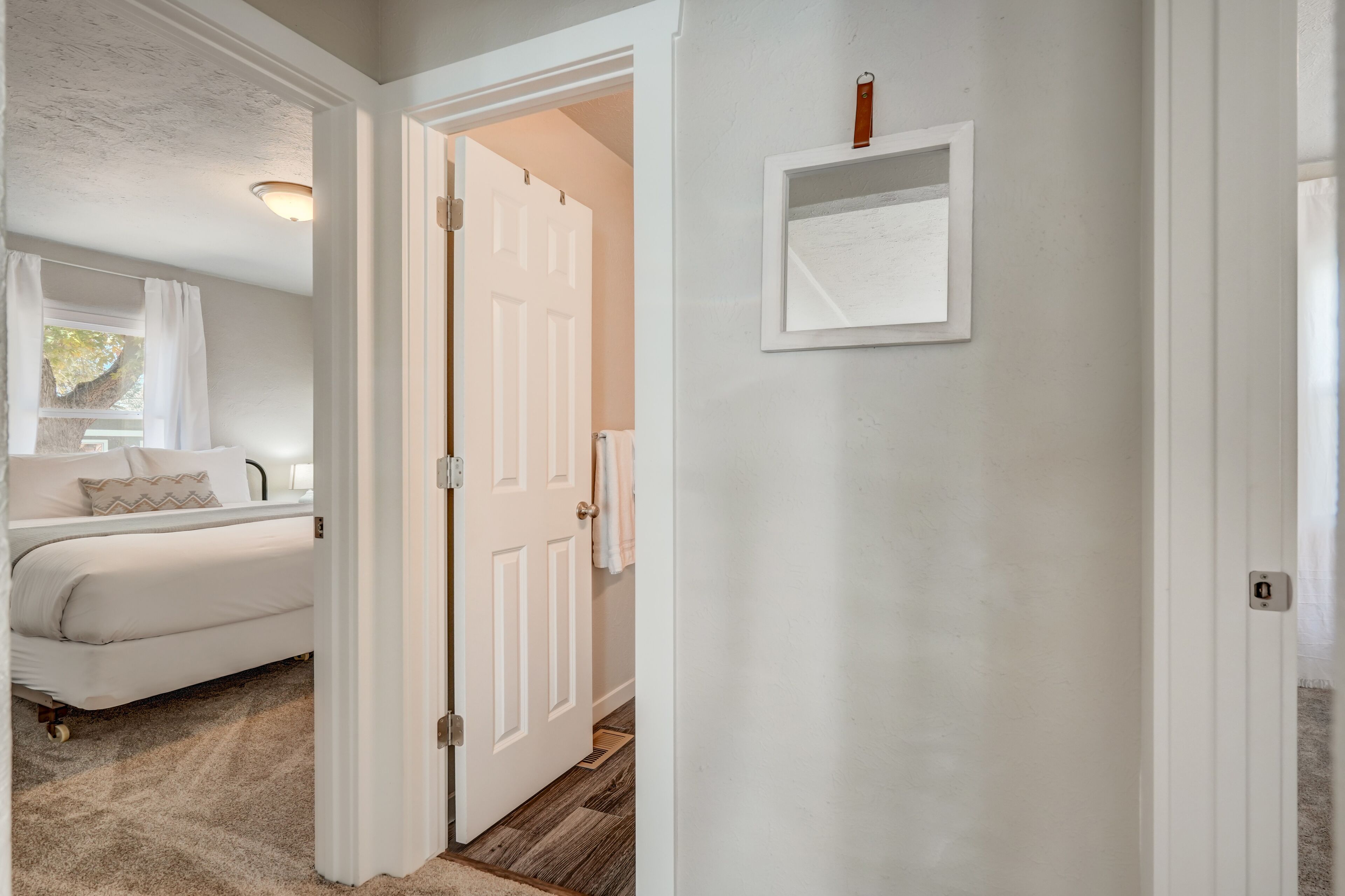 A bedroom with a bed, a nightstand, and a window with curtains.
