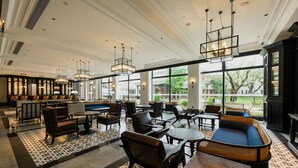 Un vaste espace intérieur aménagé avec différents types de sièges, notamment des canapés et des fauteuils, ainsi qu’un coin bar équipé de tabourets.