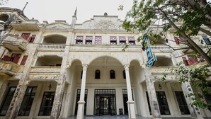 Un bâtiment historique doté d’une entrée centrale, de plusieurs balcons et d’un drapeau.