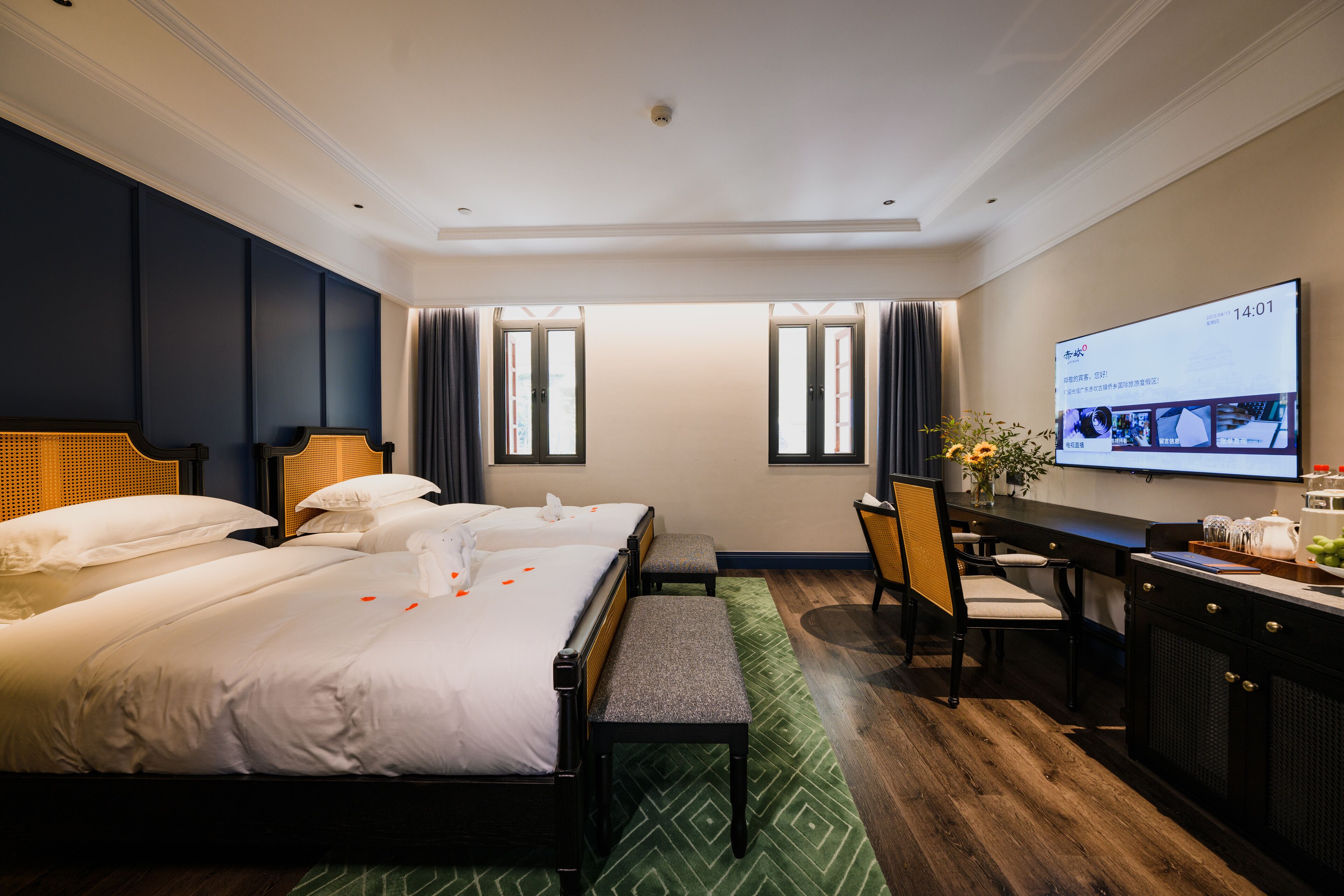 A hotel room with two beds, a desk, a chair, and a television on the wall.