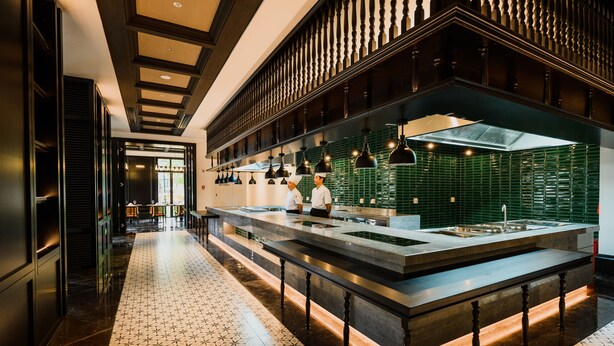 Une cuisine moderne dotée d’un îlot central, de barrières noires et d’un sol à motifs.