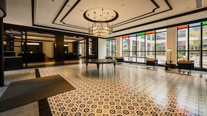 Un hall d’entrée spacieux, doté d’un sol à motifs, d’une table centrale et d’un lustre.
