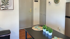 A modern kitchen with a black countertop, a stainless steel refrigerator, and a wall-mounted clock. - Serene Urban Oasis (Louisville)