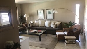 A living room with a sofa, armchairs, a coffee table, and a lamp. There are two framed pictures on the wall. - In the Heart of Palm Desert! (Palm Desert)