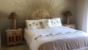 A bedroom with a large bed, two nightstands, a ceiling fan, and a decorative wall piece. - In the Heart of Palm Desert! (Palm Desert)