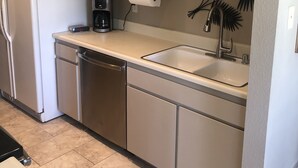 A compact kitchen with a refrigerator, dishwasher, coffee maker, and a sink with a modern faucet. - In the Heart of Palm Desert! (Palm Desert)