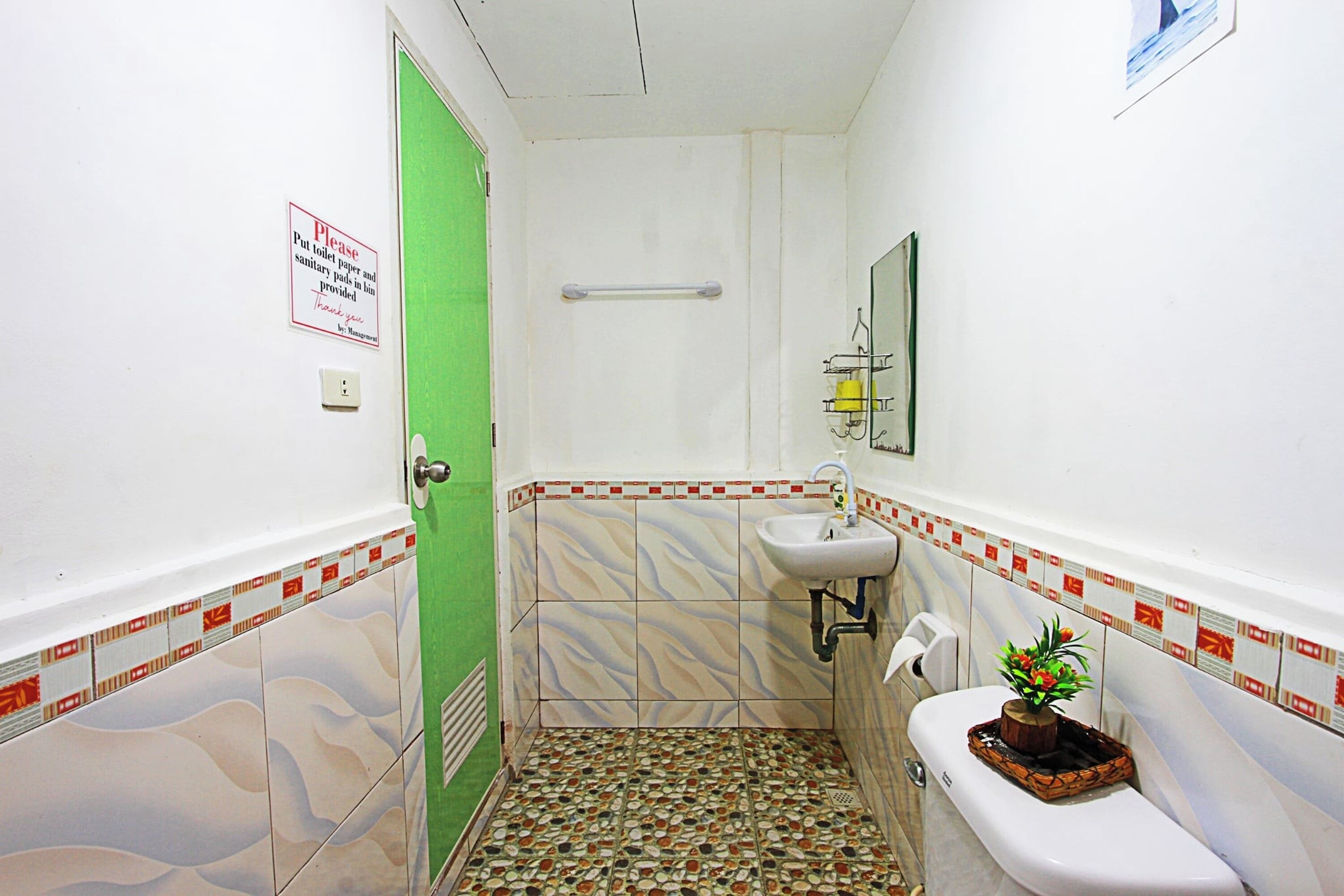 A bathroom with a green door, a sink, a toilet, and a shower area.