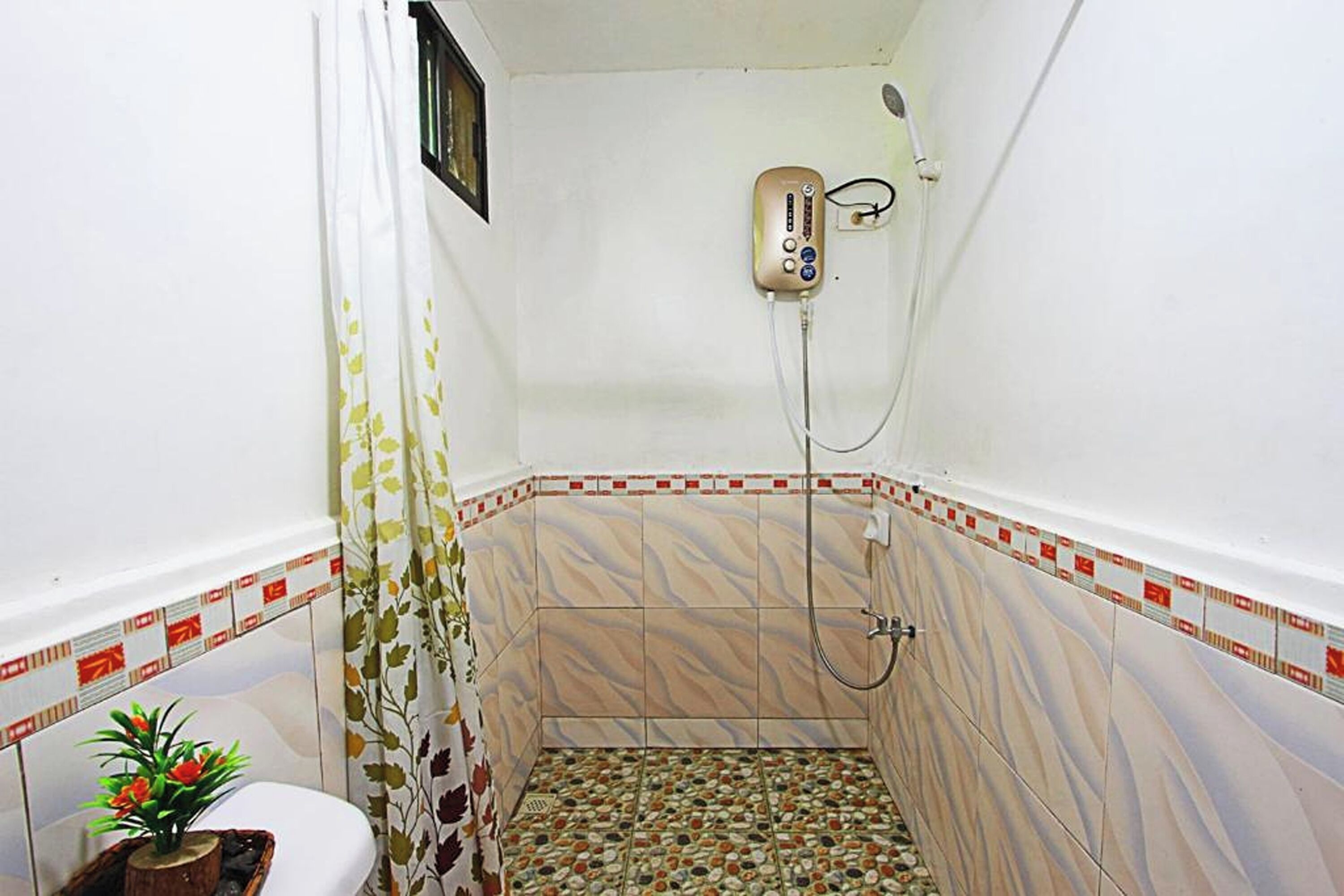 A small bathroom with a shower, a toilet, and a decorative plant.