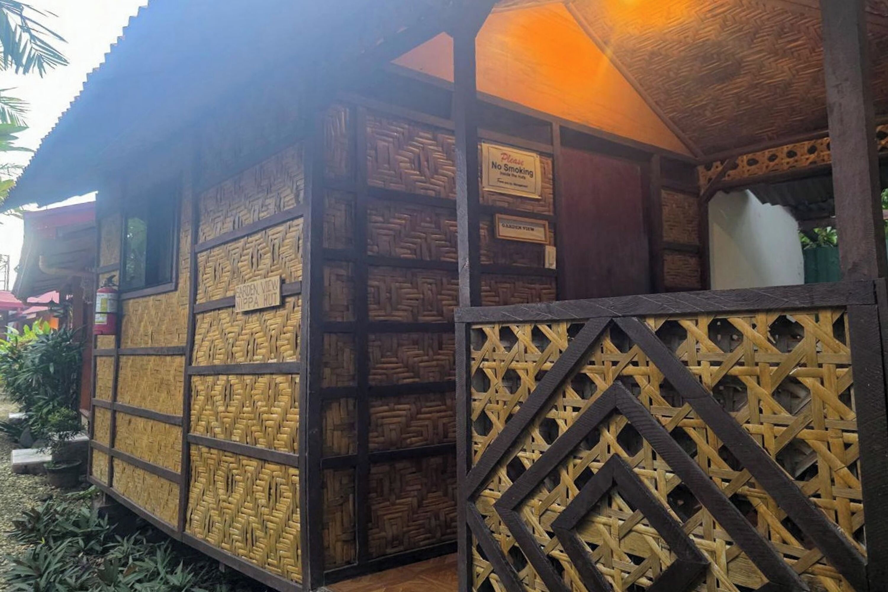 A traditional wooden structure with intricate patterns, a 'No Smoking' sign, and a 'Garden View' sign.