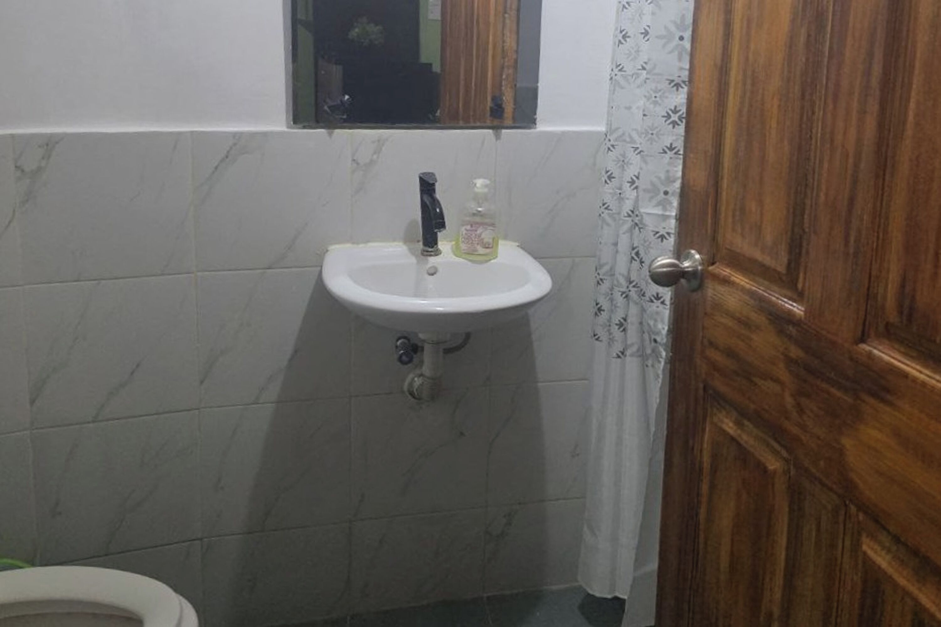 A bathroom with a white sink, a mirror above it, and a wooden door.
