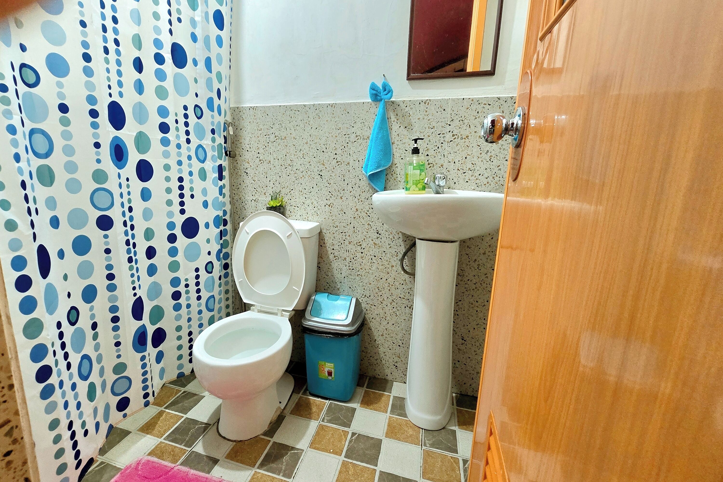 Ett badrum med toalett, handfat och en blå soptunna.