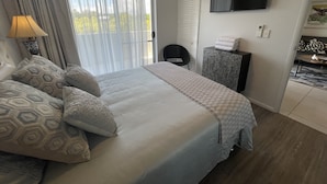 A hotel room with a bed, a TV mounted on the wall, a bedside table, and a view of the outdoors through the window. - City Stadium 2 (Townsville)