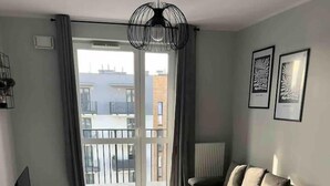 Ein modernes Wohnzimmer mit einer Couch, einem weißen Schreibtisch und einem großen Fenster mit Blick auf Gebäude.
