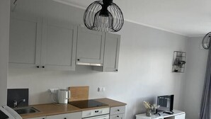 Eine moderne Küche mit grauen Schränken, einer Holz Arbeitsplatte, einem eingebauten Ofen und einem Essbereich in Weiß mit einem Fernseher.
