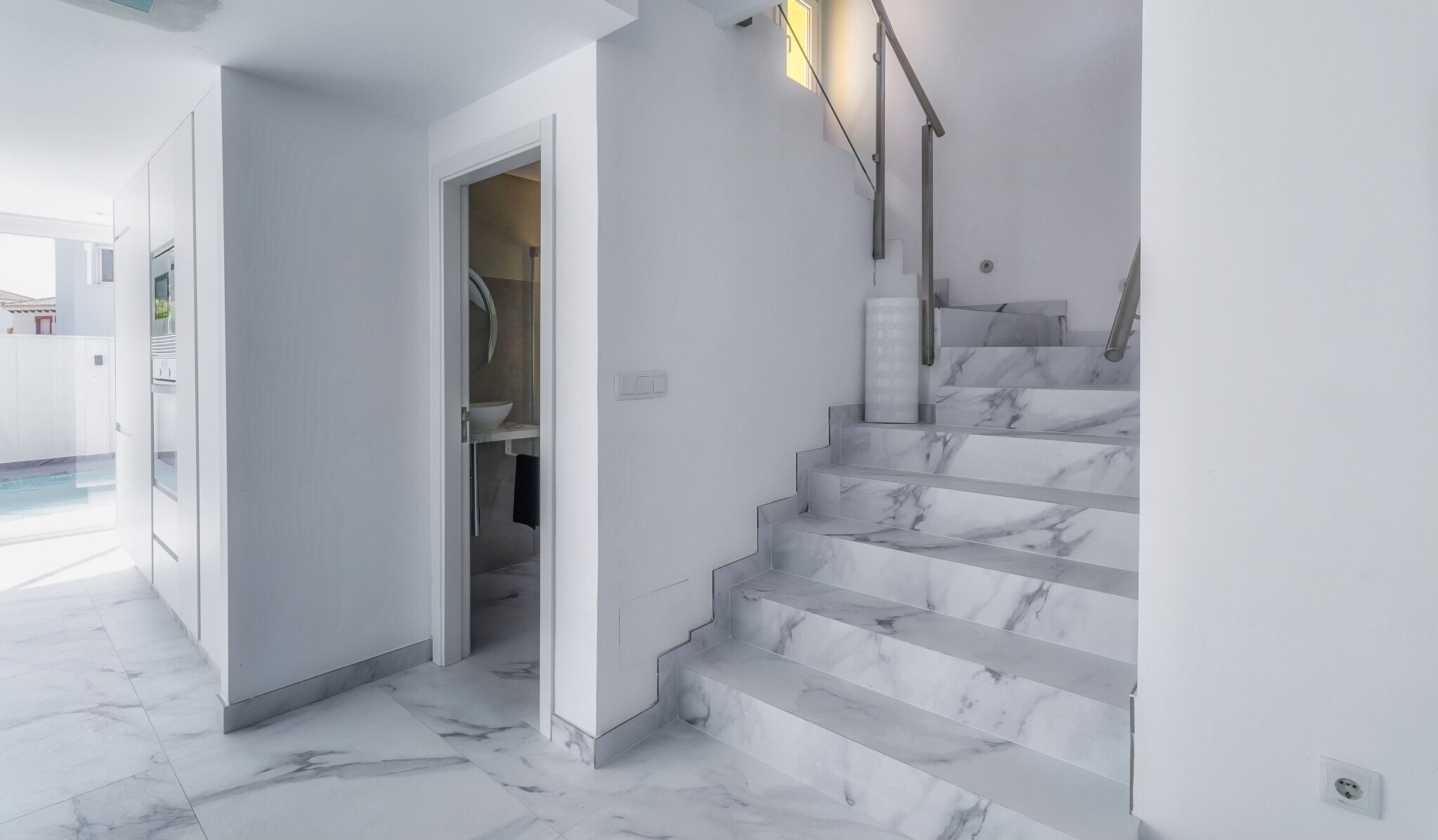 Ein modernes Interieur mit einer Marmortreppe, einem sichtbaren Badezimmer und einem Poolbereich.