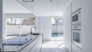 Eine moderne Küche mit Marmorarbeitsplatte, Backofen und Blick auf einen Swimmingpool.
