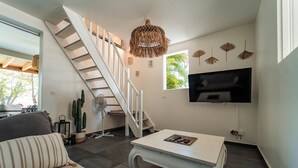 Ein Wohnzimmer mit Treppe, Flachbildfernseher und Couchtisch.