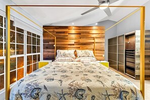 Un dormitorio con cama, paredes de madera, ventilador de techo y armario.