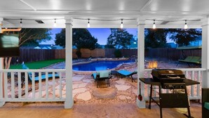 A covered outdoor area with a pool, lounge chairs, and a barbecue grill. - 5 BR w/pool, minutes to Six flags, AT&T stadium (Grand Prairie)