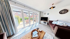 A living room with a TV, sofa, and a large sliding glass door leading to a patio.