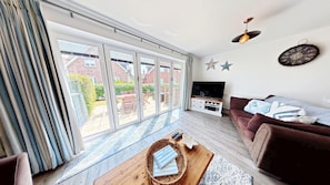 A living room with a TV, sofa, and a large sliding glass door leading to a patio.