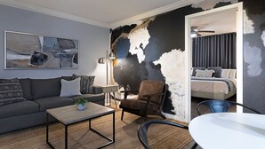 Un salon moderne avec un canapé, un fauteuil, une table basse et un tableau accroché au mur.