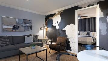 Ein modernes Wohnzimmer mit Sofa, Sessel, Couchtisch und einem Bild an der Wand.