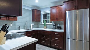 Une cuisine moderne avec des meubles de rangement en bois foncé, un réfrigérateur en acier inoxydable et une cuisinière encastrée.