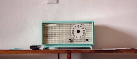 Sinivihreä radio puupöydällä valkoista seinää vasten.