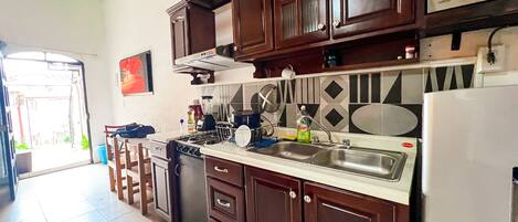 A kitchen with dark wooden cabinets, a stainless steel sink, and a refrigerator.