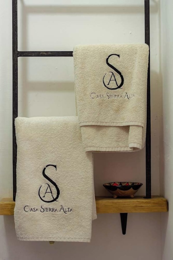 Two towels hanging on a rack, each with a monogrammed letter 'S' and the text 'Casa Sierra Alta'. - Casa Sierra Alta (Taxco)