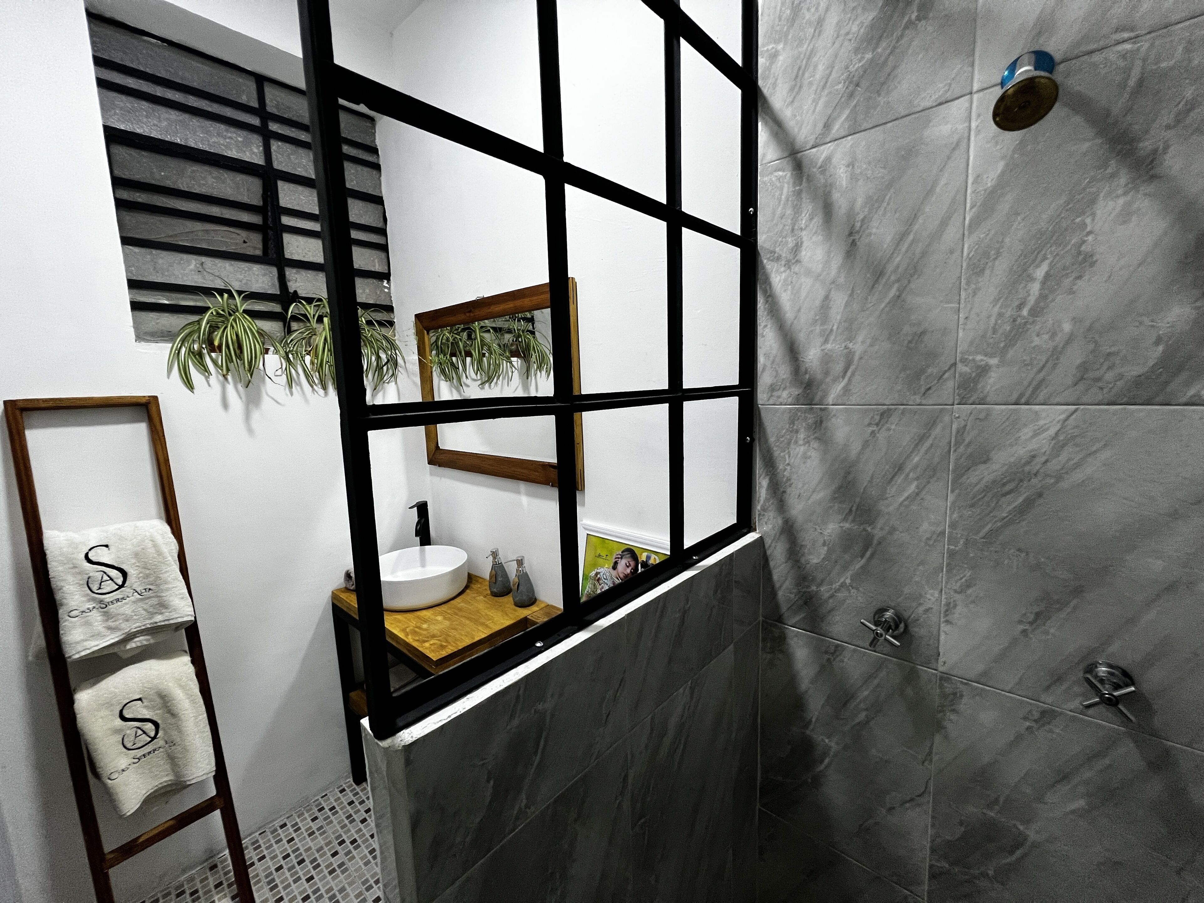 A modern bathroom with a large mirror, a sink, and a shower area.