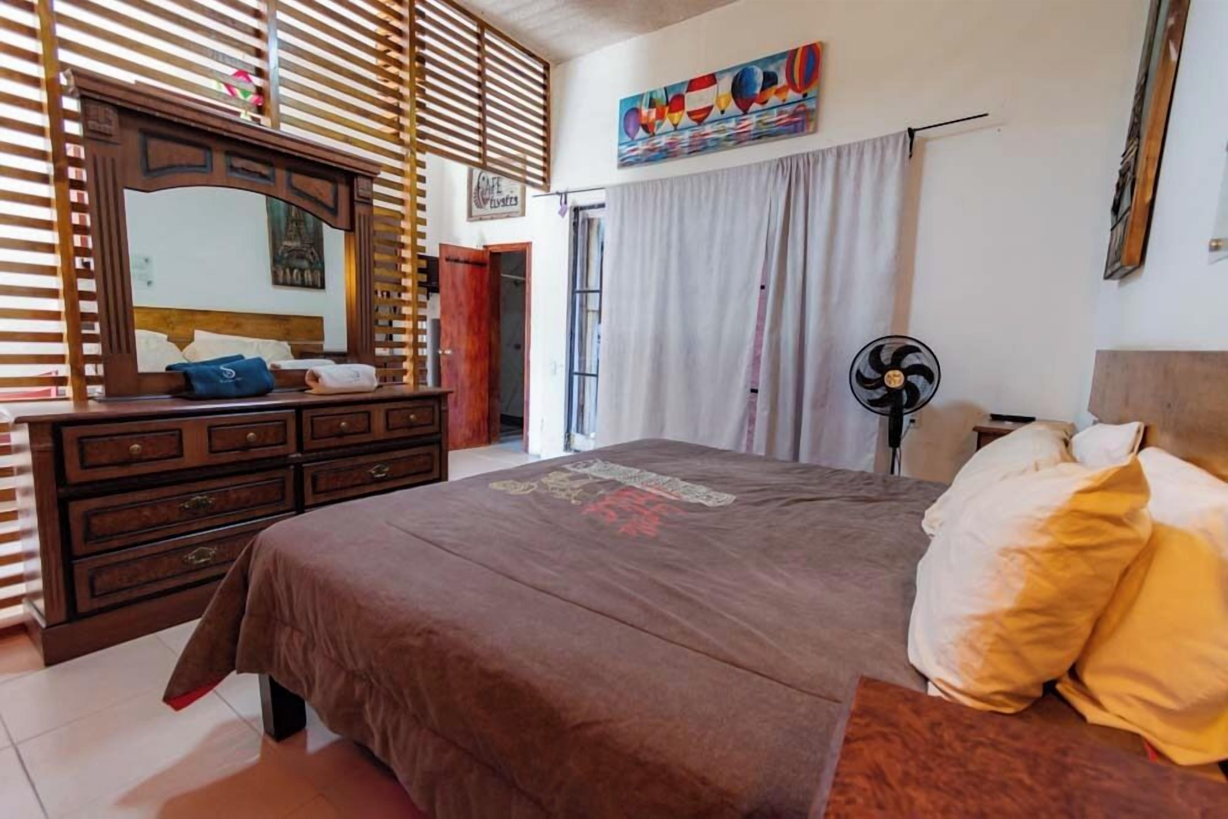 Un dormitorio con una cama grande, cómoda de madera y un espejo.