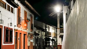 Una calle estrecha flanqueada por edificios, con balcones y un letrero que dice "Hotel".