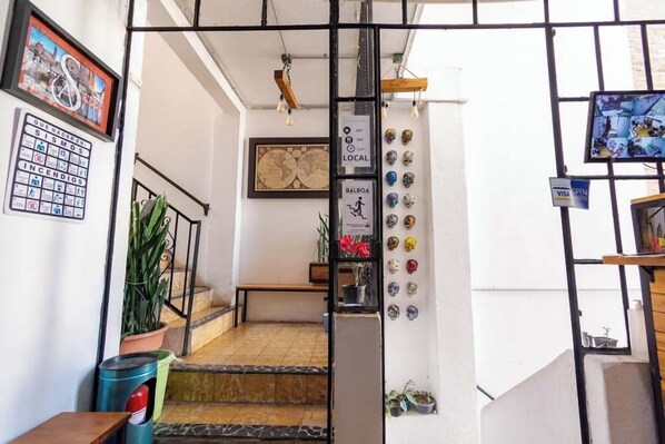 A staircase with a metal railing, a potted plant, and a wall with various signs and decorations. - Casa Sierra Alta (Taxco)