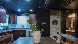 Una cocina moderna con armarios de madera oscura, salpicadero de ladrillo blanco y lavadora integrada.