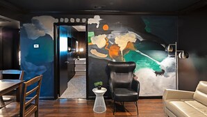 Un interior moderno con un gran mural abstracto, un sillón de cuero, una mesita redonda y un sofá.