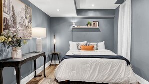 Une chambre à coucher avec un lit, un bureau, une lampe et un tableau au mur.