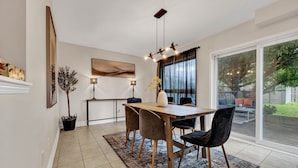 Un espace repas moderne avec une table en bois, des chaises noires et un tapis à motifs.