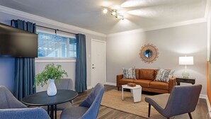 A modern living room with a brown leather sofa, a round table, and blue chairs.
