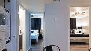 Habitació d'hotel amb un llit, un ventilador de sostre i una rentadora a la cantonada.