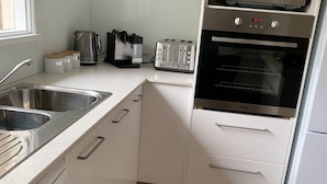 A modern kitchen with white cabinets, stainless steel appliances including a microwave, toaster, and oven, and a Bosch dishwasher.
