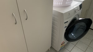 A laundry area with a washing machine, a dryer, and a white basket on top of the dryer.