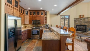 Una cocina con armarios de madera, electrodomésticos de acero inoxidable, encimera de granito y chimenea de piedra.